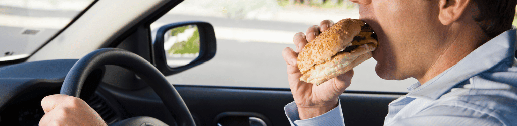 Man eating cheese burger while driving 