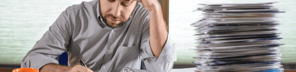 Man calculating expenses with a stack of bills next to him