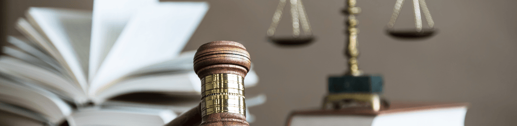 Gavel, Scales of Justice, and a law book are sitting on a desk.