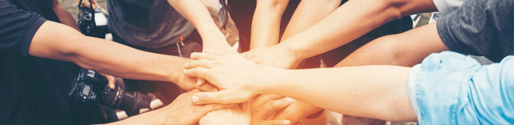 A group of people putting their hands together to cheer